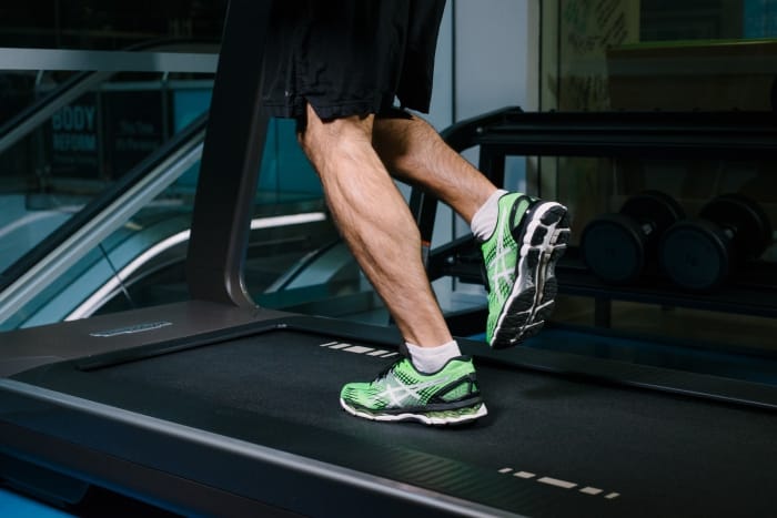 close up of man's legs with trainers on running on a treadmill