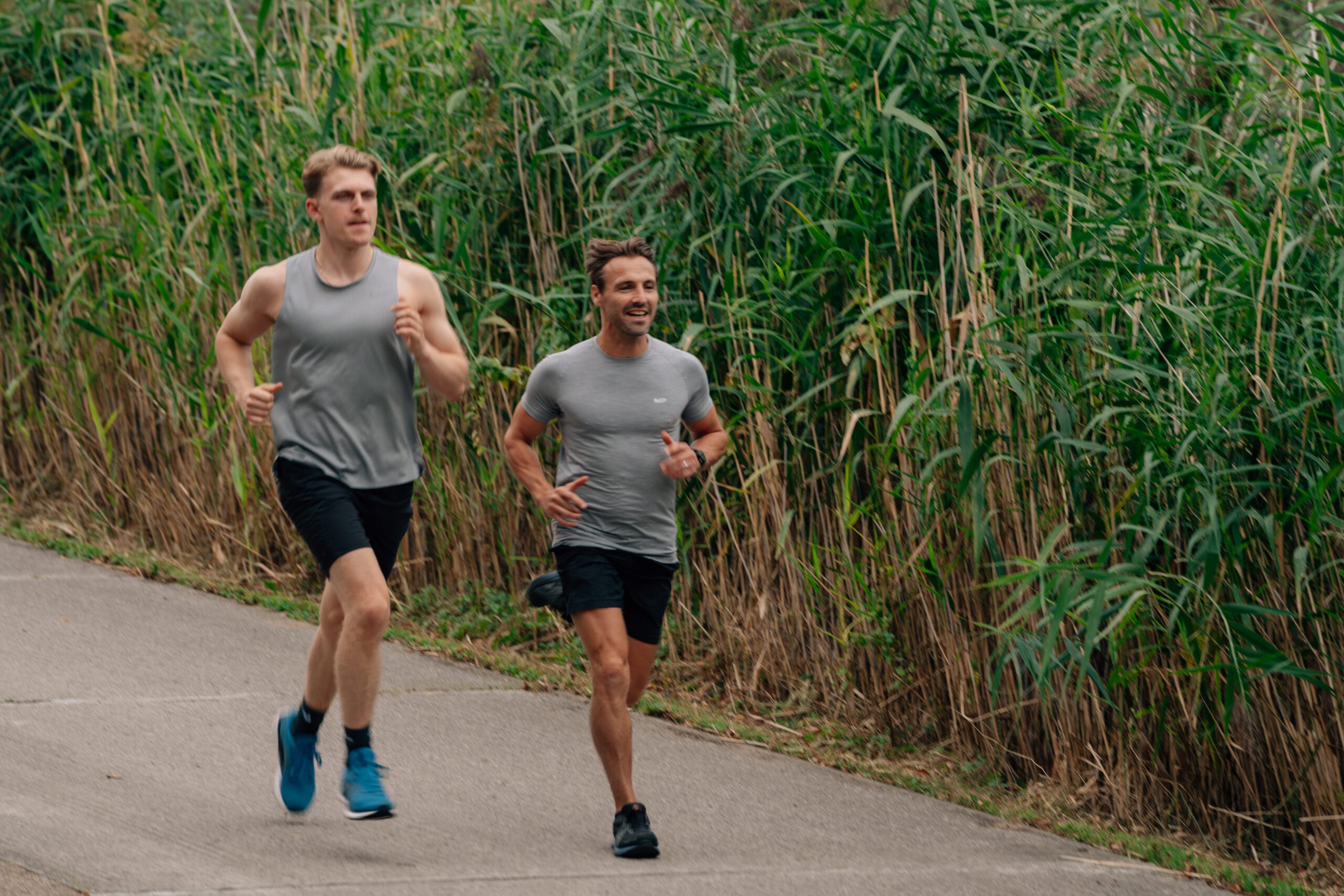 two men running near some reeds