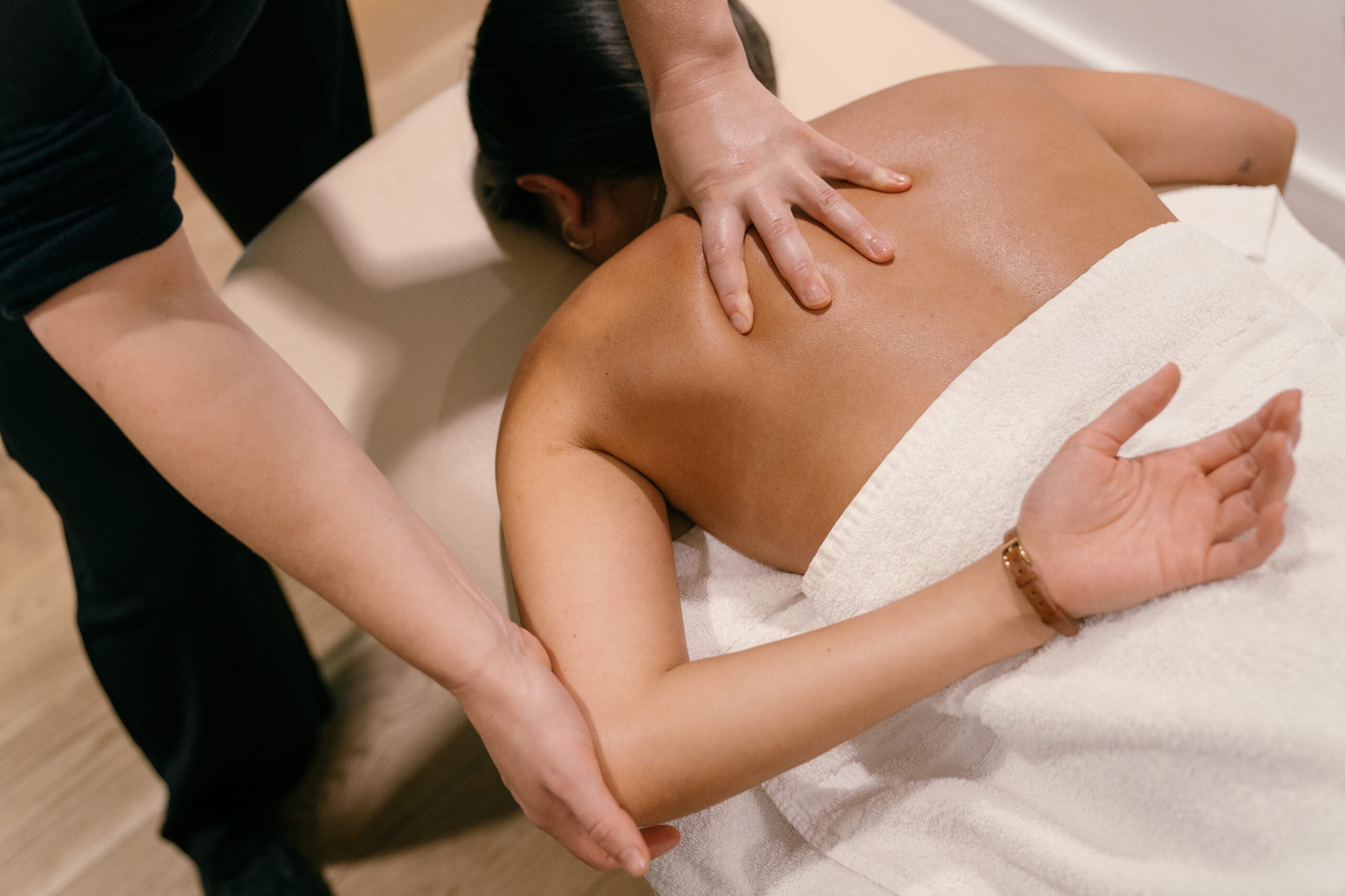 Soft tissue therapy hands massaging patient's back on bed