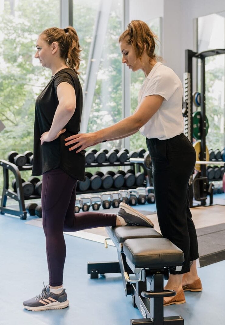 clinician assisting patient in recovery gym with hands on hips