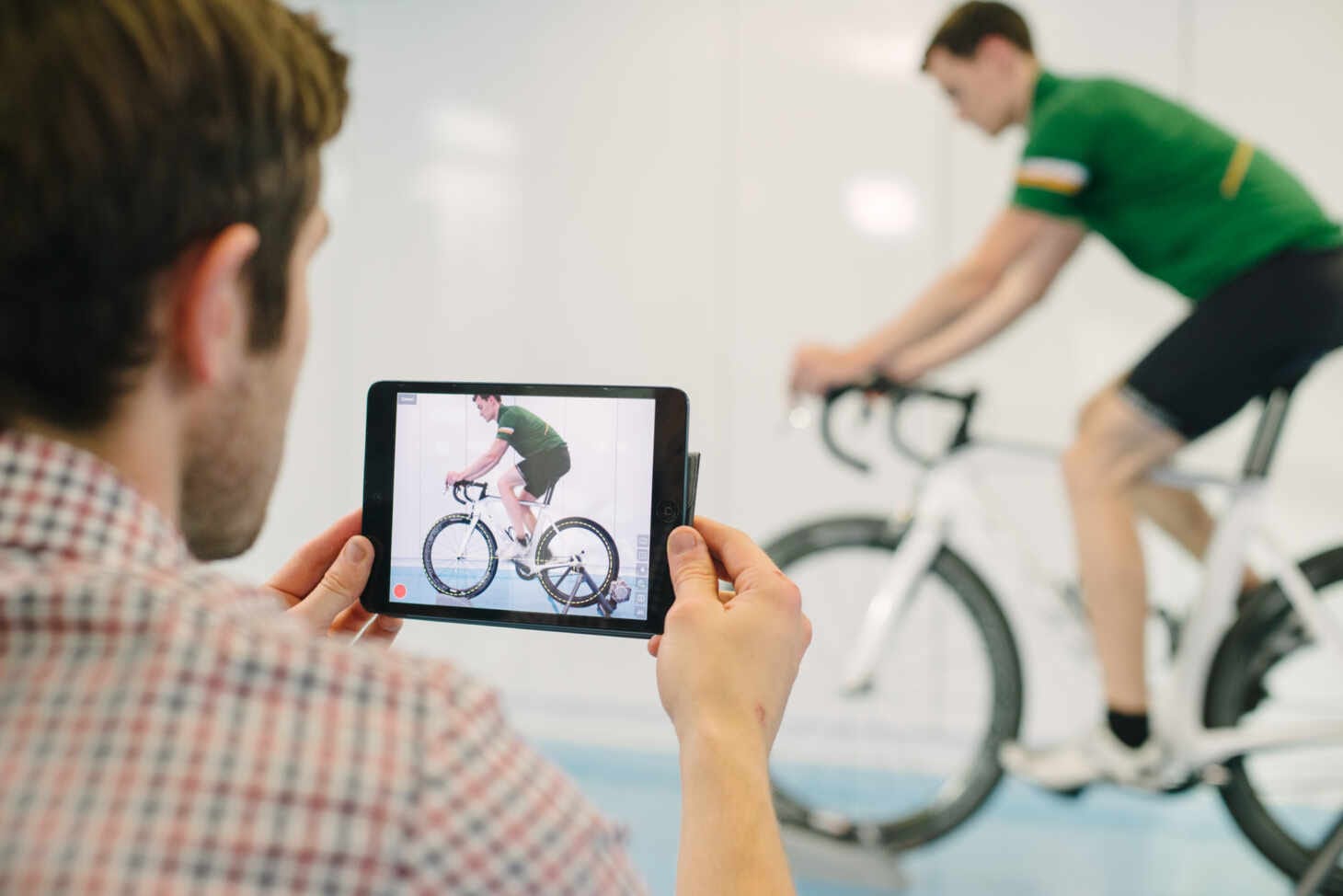 a man holding up a tablet camera with man riding a bike