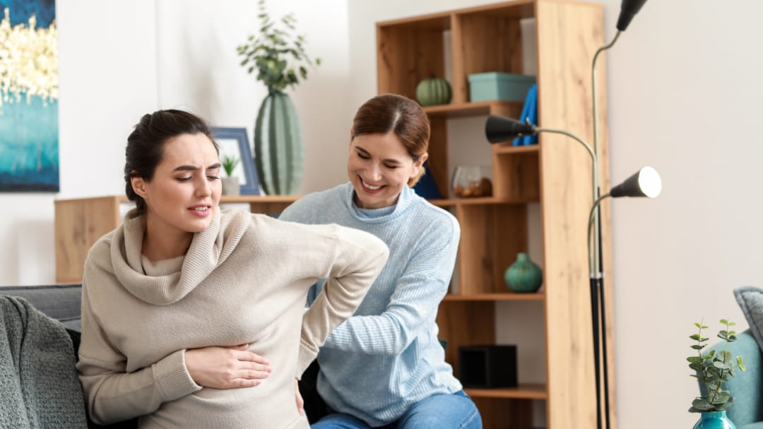 one woman helping another pregnant women on chair
