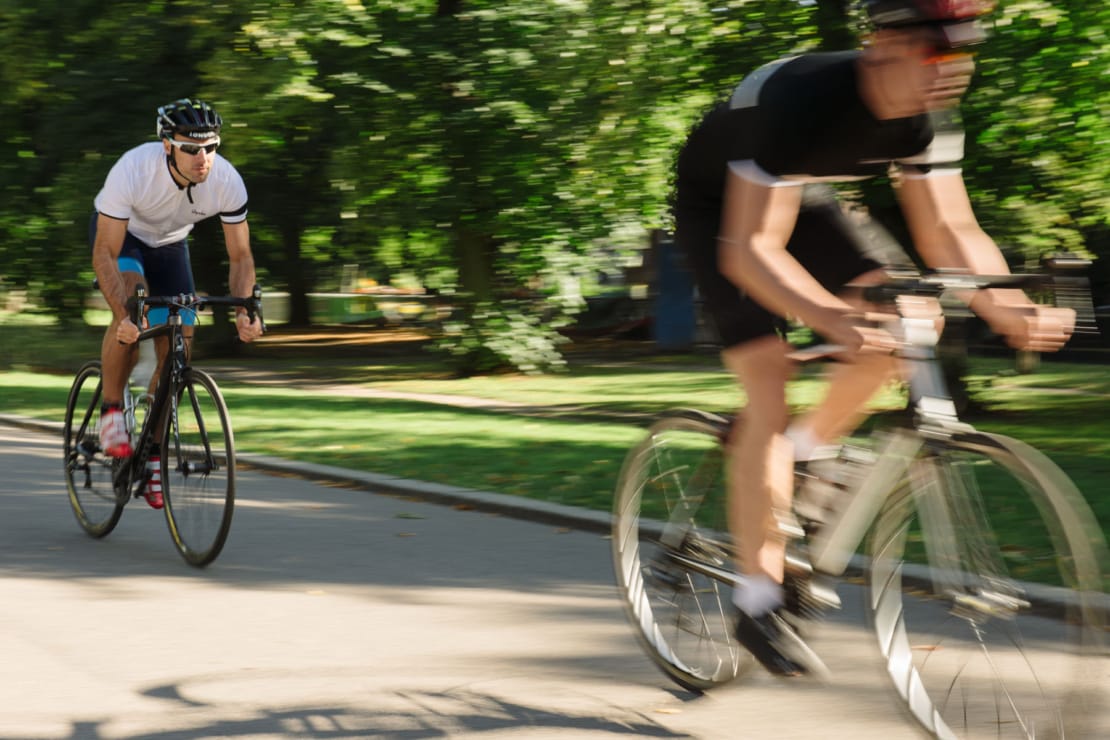 two men on bikes cycling fast in the park