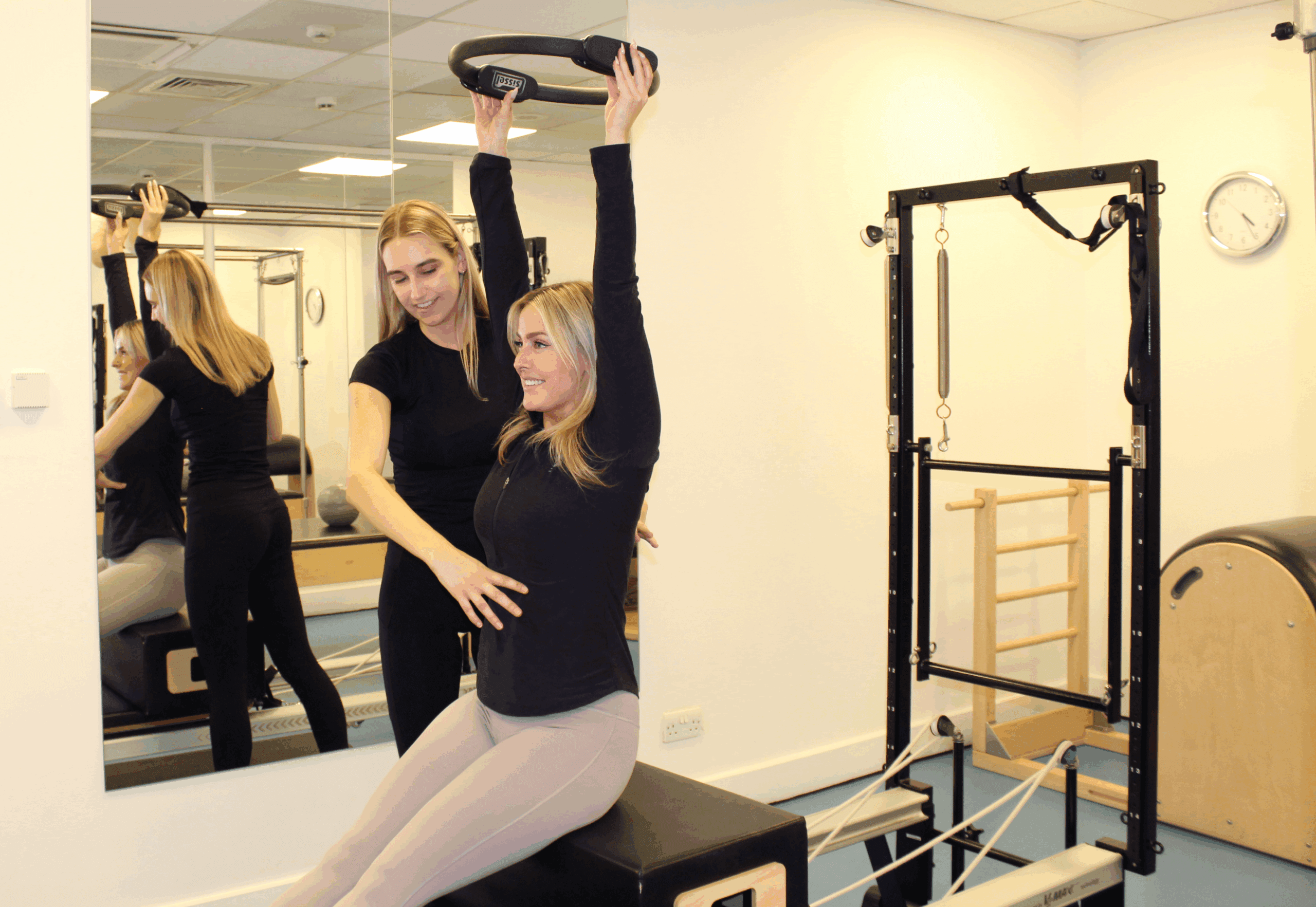 clinician supporting woman sat on bench with arms up